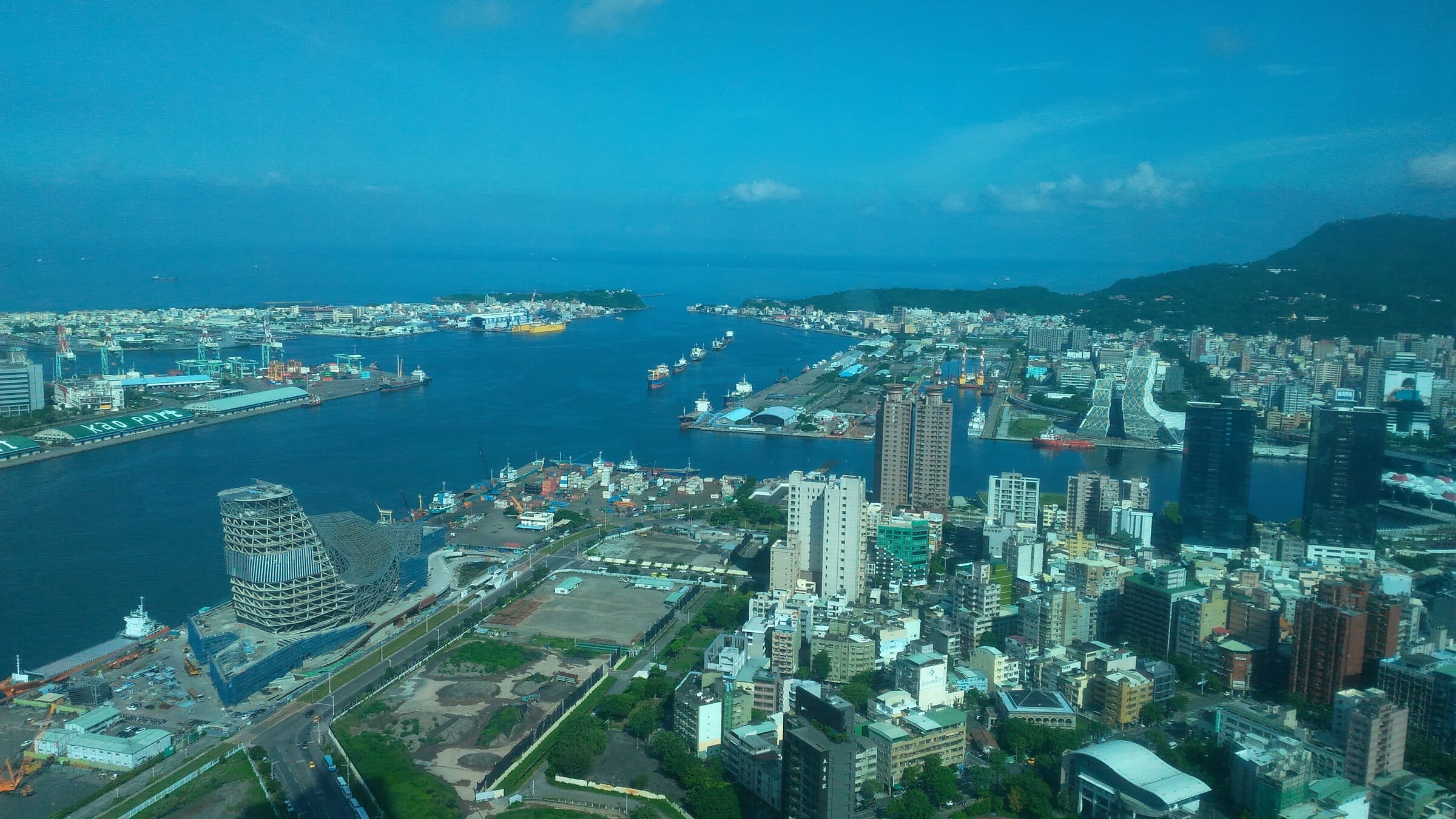Archival panoramic view of the Port of Kaohsiung, Taiwan, showing harbor channels, cargo facilities and the city in July 2019.